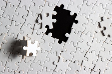 disassemble incomplete white jigsaw puzzle pieces with plain black empty space on its centre