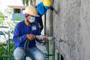Plasterers using and operating sprayer mortar equipment machine for spraying mortar concrete cover...