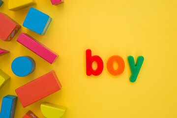 Kids Education, Creative, logical thinking concept. Colourful multicoloured building wooden toy blocks for children learning development word Boy from plastic letters on yellow background flat lay