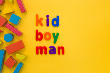 Development, human adulthood, maturing, education upbringing concept. Man's growing up. Colourful words from plastic letters Kid Boy Man on the yellow background