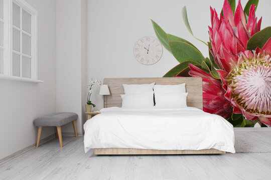 Stylish interior of bedroom with beautiful exotic flowers on wall