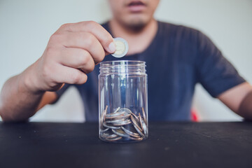 Man holding coins putting in glass, saving money for finance accounting concept.