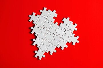 heart shaped jigsaw puzzle icon logo symbol on plain red background