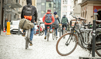 People on bicycles with backpacks travel around the city center. Fashion for ecological city tours. Two day trip. Rear view.