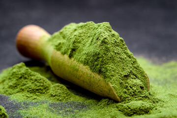 Green tea, matcha. Powdered young barley or wheat grass on wooden scoop. Detox superfood concept.