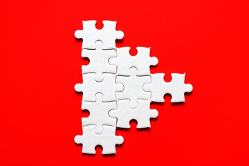 white jigsaw puzzle resemble small  triangle or play logo icon button on plain red background  