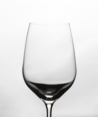 Close up and Front view of clear empty wine glass with beautiful lighting and white background shows elegant crystal glassware for luxurious beverage in restaurant, winery and celebrating party.