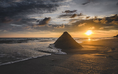 Sand pyramid and sea wave with outdoor sunset low lighting.
