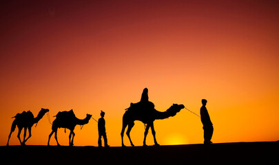 Fototapeta na wymiar Indian men walking through the desert with their camels