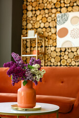 Vase with lilac flowers on table in stylish room