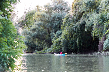 Girl in a blue kayak on a wilderness river near green trees