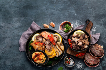 Grilled seafood variety with vegetables on dark background.