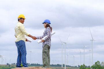 Engineers stand holding blueprints and congratulate wind turbine projects to generate electricity and check wind direction.