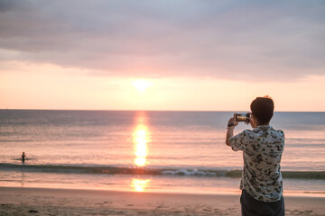 Fototapeta premium Vacation and technology. Young man using smartphone on sand beach. travel concept