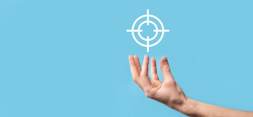 Targeting concept with hand holding target icon dartboard sketch on chalkboard. Objective target and investment goal concept.