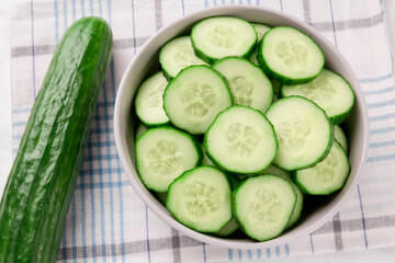 Pile of fresh sliced cucumbers in bowl on white background