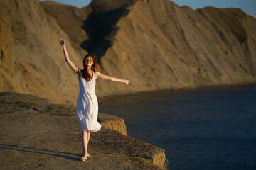 a woman in a dress walks along the beach in nature in the mountains in summer