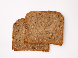 Two slices of wholegrain bread with seeds of sunflower, flax, and sesame. Healthy vegetarian food. Isolated flatlay.