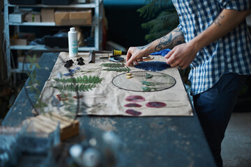 Male herbalist in plaid shirt making herbarium at home - obrazy, fototapety, plakaty