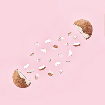 Creative Concept Of The Fresh, Organic Coconut Cut In Half With Small Pieces. .Healthy Fruit Explosion On Pastel  Pink Background.