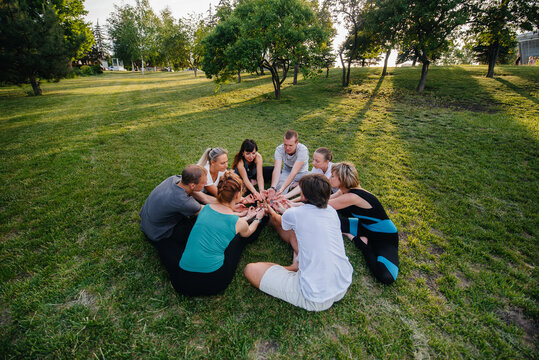 A group of people do yoga in a circle in the open air during sunset. Healthy lifestyle, meditation and Wellness