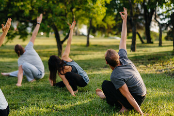 Un groupe de personnes fait du yoga dans le parc au coucher du soleil. Mode de vie sain, méditation et bien-être
