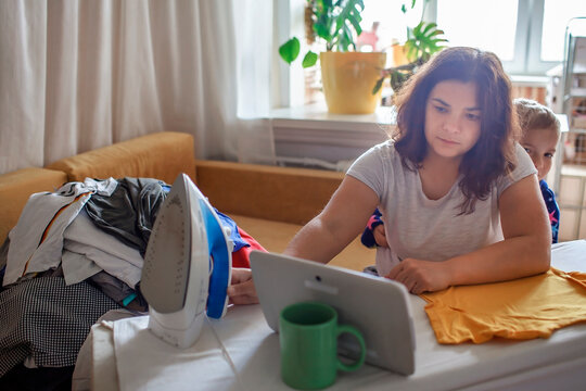 Middle aged mom and son talk to relatives via Internet while doing household chores, social media and gadget addiction, social distance and lockdown, new reality
