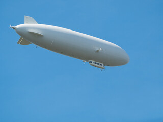 Cigar-shaped gray airship flies high in clear blue sky