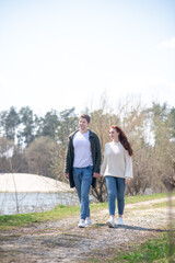 Fototapeta premium Happy woman and man holding hand walking outdoors