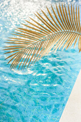 Fototapeta na wymiar Blue water texture in a swimming pool with palm leaf