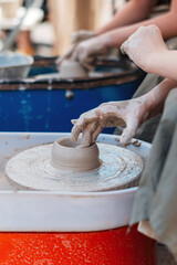 The hand of a person creates a clay figure in pottery