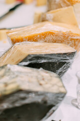 Handmade cheese wrapped in polyethylene lies on the counter