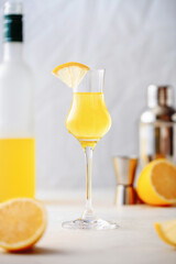 Limoncello in glass, sweet Italian lemon liqueur, traditional strong alcoholic drink and lemons .