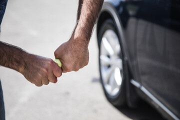 a man squeezes out a rag near the car
