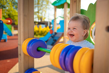 Portrait of happy funny caucasian baby girl playing on the playground. Outdoor. Happy children's day