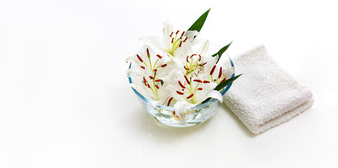 Transparent vase with water and white lilies with a white towel. Isolated on white. Spa concept for cleanliness, freshness and aromatherapy.