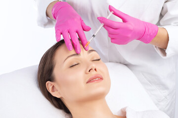 Cosmetologist makes rejuvenating anti wrinkle injections on the face of a beautiful woman. Female...