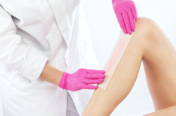 Fototapeta premium A beautician makes a sugar paste depilation of a woman's legs in a beauty salon. Female aesthetic cosmetology.