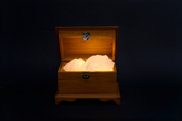Open treasure chest filled with glowing treasure isolated on black background
