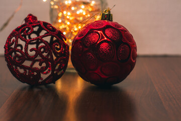 Red Christmas balls and golden Christmas lights. Decorations for the New Year 2022. Christmas ornaments for winter holidays close-up. Copy space