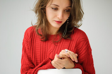 Studio portrait of young woman in red knitted sweater and earring on white background