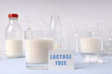 Closeup of glass of milk sign and test Lactose Free, lab glassware on the blue sirface against white wal