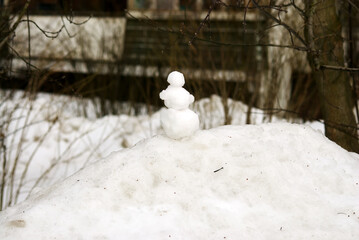 a very small snowman stands on a snowdrift