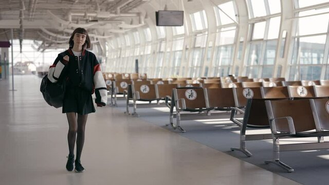 Stylish woman with short haircut walking at empty airport