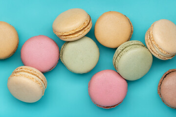 Round multicolored macaroons on a bright blue background. Background and wallpaper, close-up.