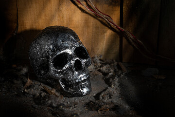 silver skull on a pile of dirt and dust against the background of old walls made of hewn boards in...