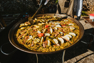 Typical Spanish paella being cooked for a big party outdoors on a sunny day
