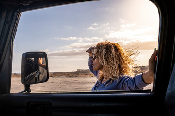 Attractive woman outside the car look the road in adventure travel - freedom lifestyle adult female with vehicle - concept of people and roadtrip vacation - sky and colorful sunset in background © simona