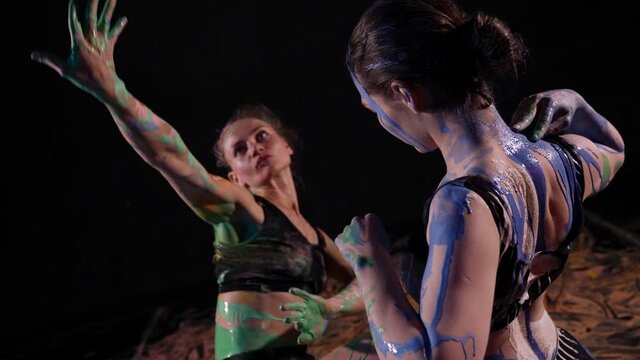 Women dancing with colored face art and body paint. Art dance with bright makeup and body art.