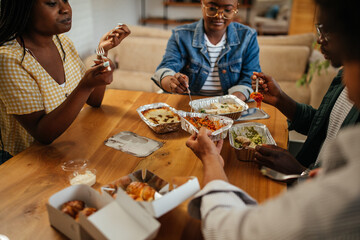 Young black friends eating take out food at home